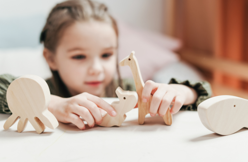 Óvodás gyermek játszik fa játékkal.